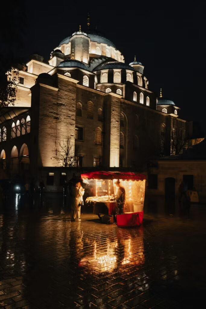 Marché de nuit devant une mosquée éclairée